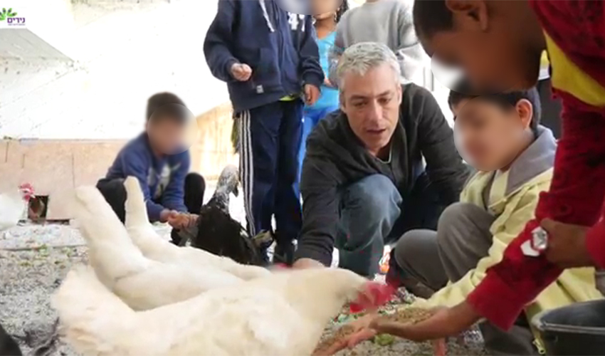 ד"ר עודד הרשקו וילדי בית הספר נירים מטפלים בבעלי החיים (צילום מתוך הסרטון "נירים 2016" ביוטיוב)