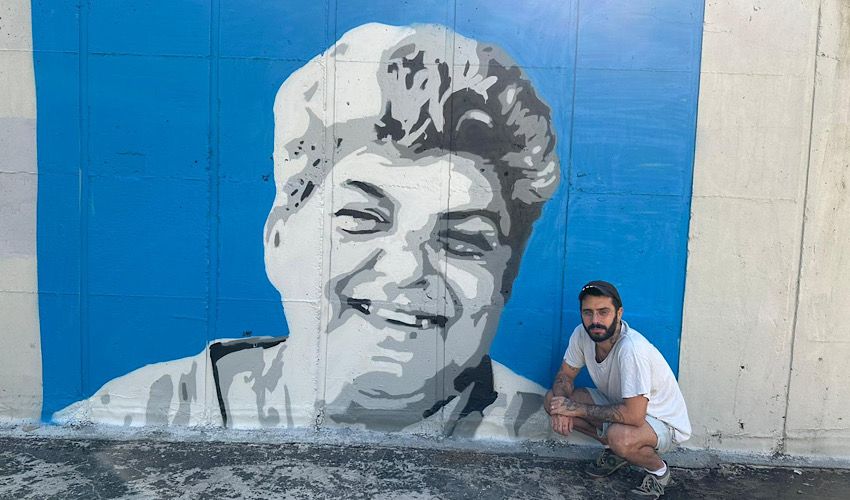 האמן עדי יונתן כהן לצד הדיוקן של רחל מאופקים (צילום: ענת סלומון, דוברות עיריית חיפה)